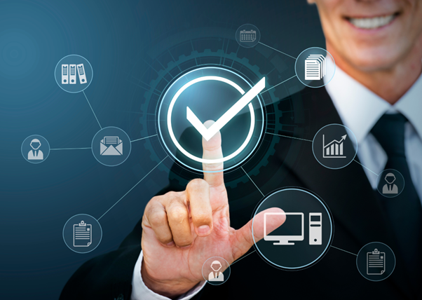 A businessman pointing at a glowing clock surrounded by icons for email, charts, security, and devices, symbolising the time savings, efficiency and access to better processes that outsourcing delivers.